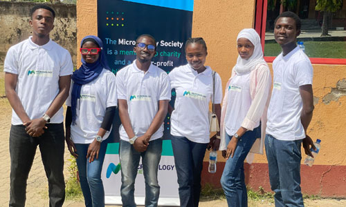 Volunteers posing for a picture in front of a Microbiology Society banner