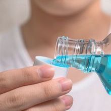 Hand of man Pouring Bottle Of Mouthwash Into Cap.jpg