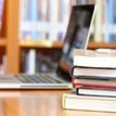 Stack of books with laptop in the background