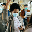 People standing on a bus wearing surgical face masks.