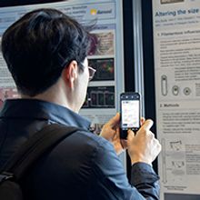 Men holding a phone, photographing a scientific poster