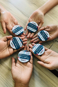 A group of hands holding badges