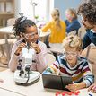 Teacher with two children doing experiments with a microscope and a tablet