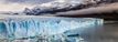 Blue glacier in the water with grey mountains in the background