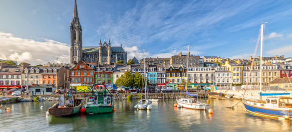 Irish quay with several docked boats as well as the town and church.