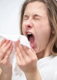 Woman sneezing and holding a white tissue