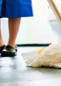 Picture shows someone's legs and their blue dress and black shoes in the background with a white mop in the front