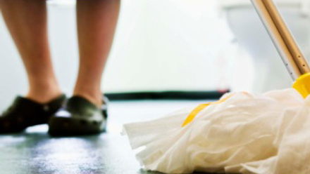 Picture shows someone's legs and their blue dress and black shoes in the background with a white mop in the front
