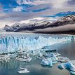 Blue glacier in the water with grey mountains in the background