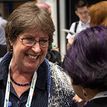 A person wearing glasses smiling and chatting.