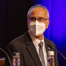 Person with glasses and a white facemask looks to the left