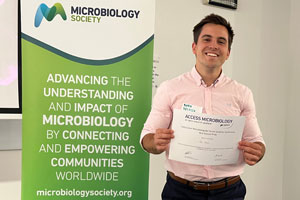 Pablo Relucio Bajo standing next to a Society banner with his certificate