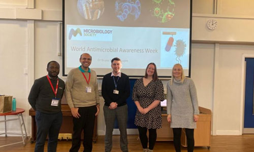 Bruno Lopes and other professionals posing in front of a Microbiology Society branded slide