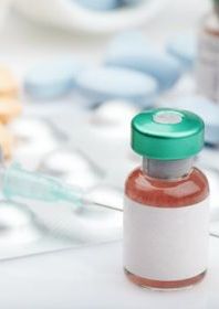 Medication bottle with syringe, bottles and pills in the background