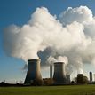 Photo of a power plant with a smoke cloud floating above.
