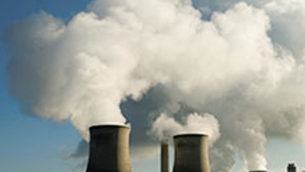 Photo of a power plant with a smoke cloud floating above.