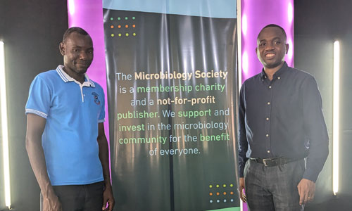 Society Champion, Yinka Somorin stood next to the Society banner with the Head of School