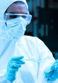 Scientist wearing a Hazmat suit, protection goggles and gloves holding a pipette and a petri dish