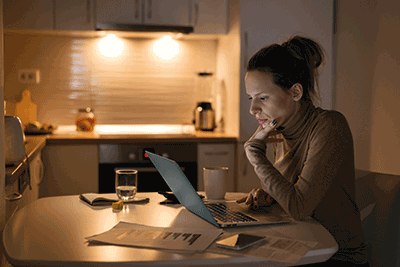 A person sitting in a kitchen on a computer.