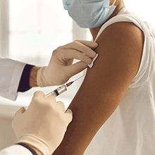 Close up picture of someone vaccinating another person in the arm